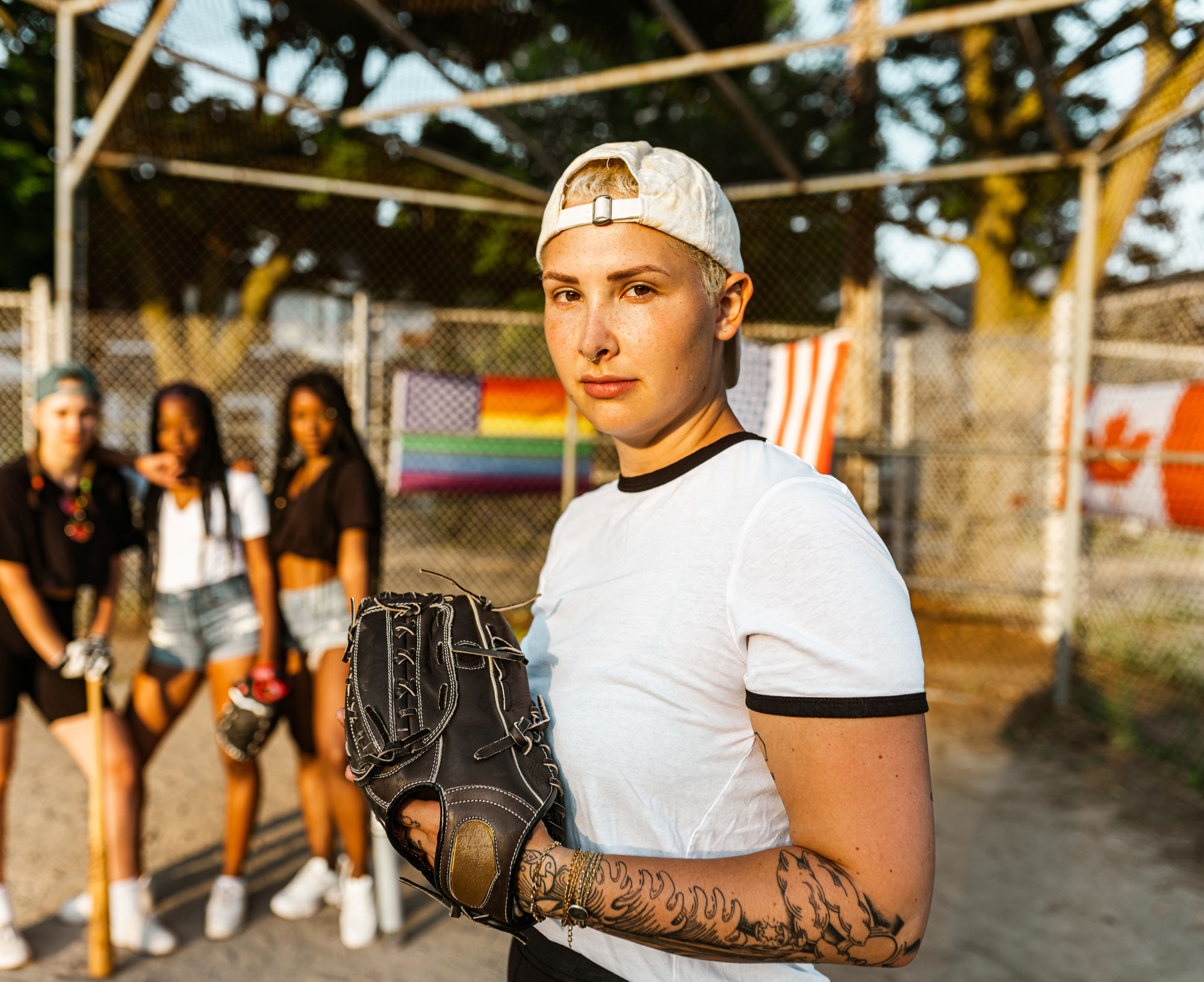 Softball player with mitt looking into camera with teammates looking on