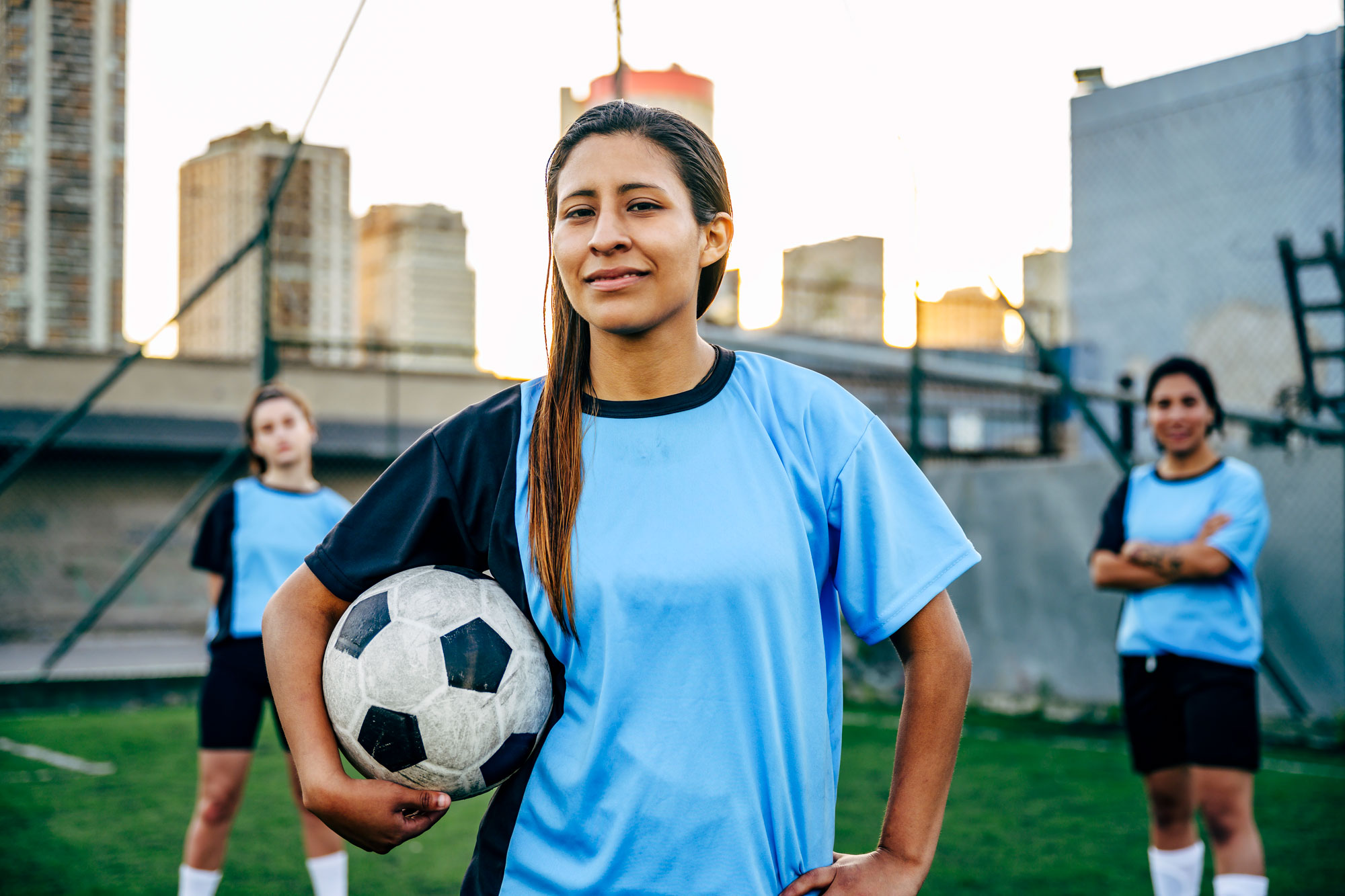 Young soccer player facing the camera, standing on the field with two teammates